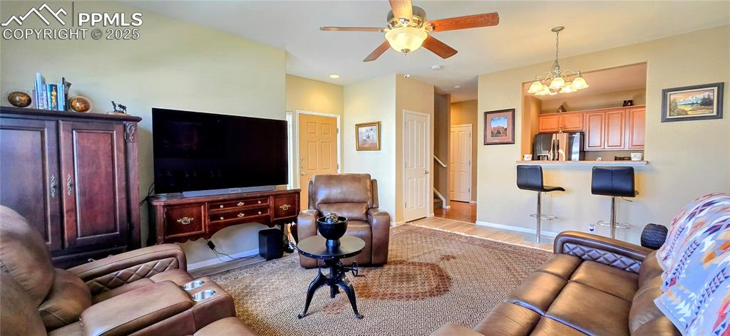 Image 6 of 37: Living room with light wood-style flooring, a chandelier, ceiling fan, and