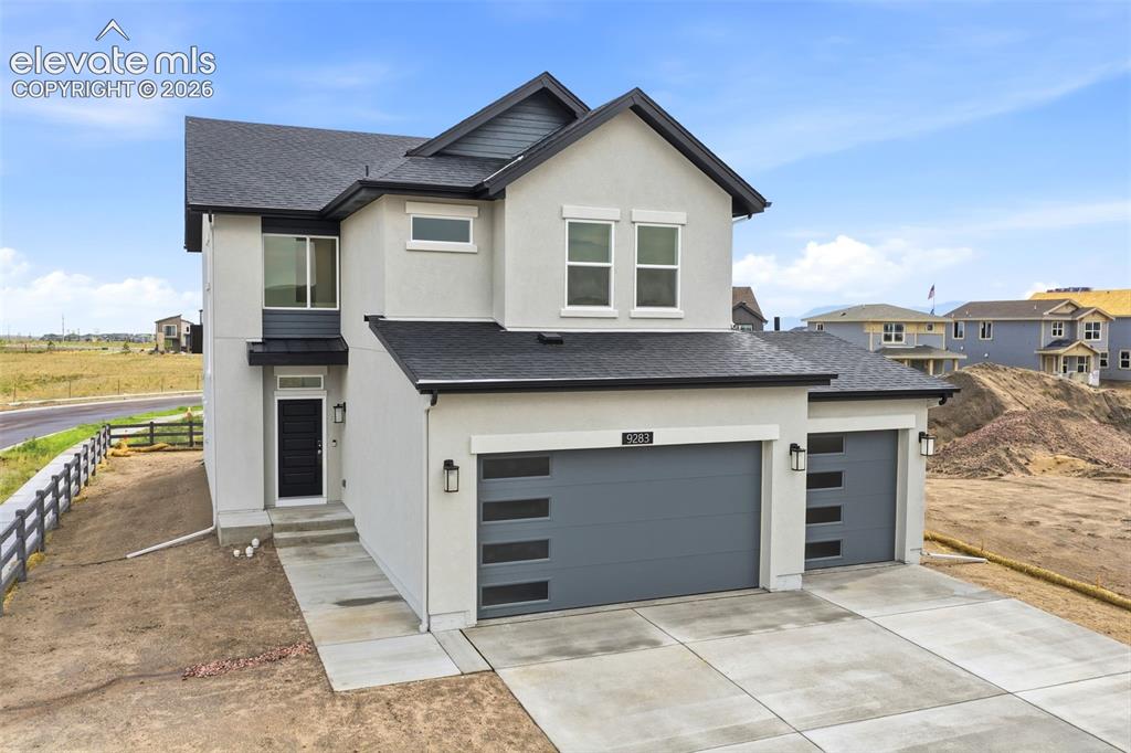 Image 2 of 29: Two-story stucco exterior with a dark-toned roof and trim