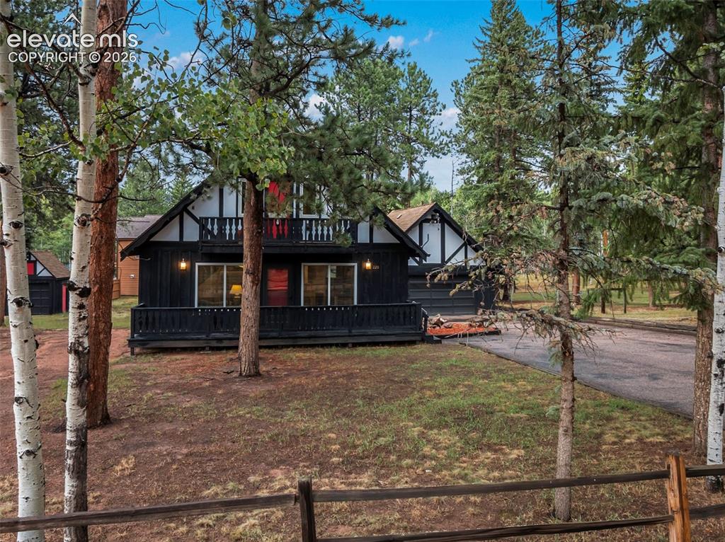 Image 11 of 40: Black exterior with white trim, upper balcony, front porch, and gravel driv