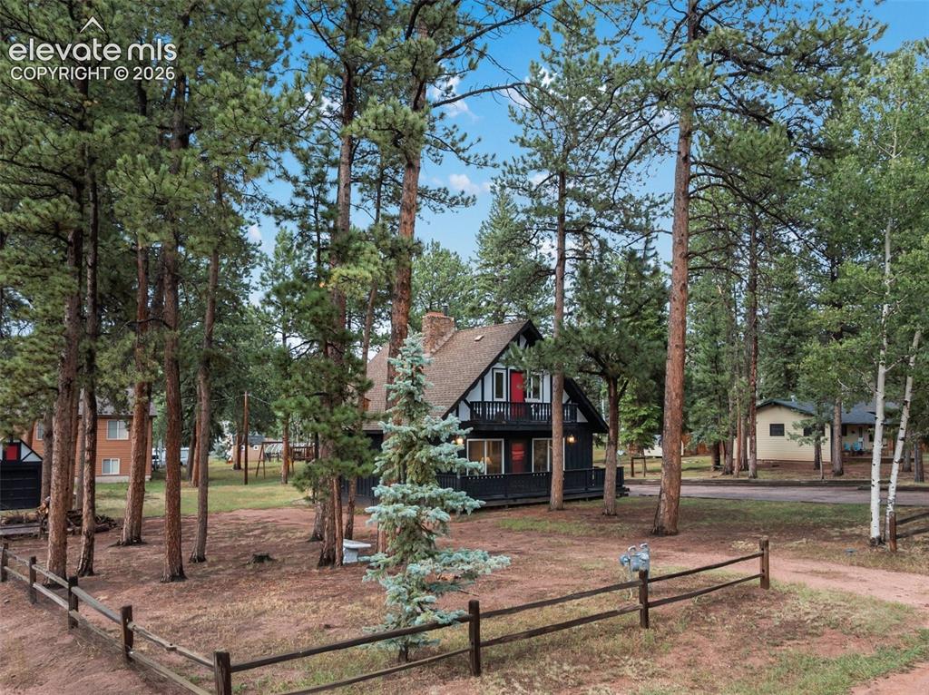 Image 12 of 40: A-frame property with a second-story balcony, prominent red front door, and