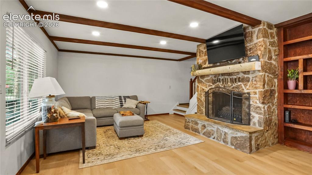 Image 15 of 40: LVP flooring, exposed ceiling beams, recessed lighting, stone-clad fireplac
