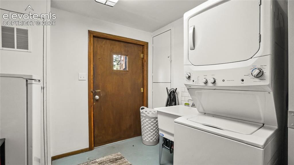 Image 22 of 40: Stackable washer and dryer, utility sink, and white subway tile backsplash,