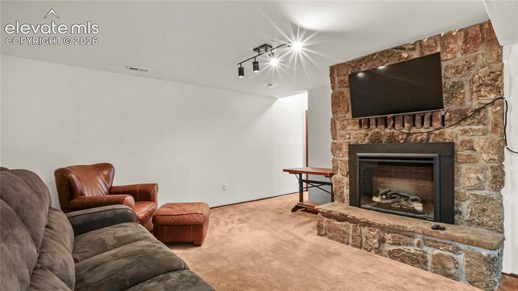Image 24 of 40: Stone-clad fireplace with a hearth, mounted TV, carpet