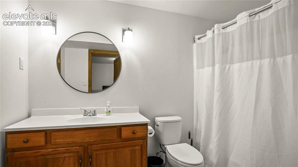Image 28 of 40: Adjoining bathroom in the basement, with vanity with wood-finish cabinetry,