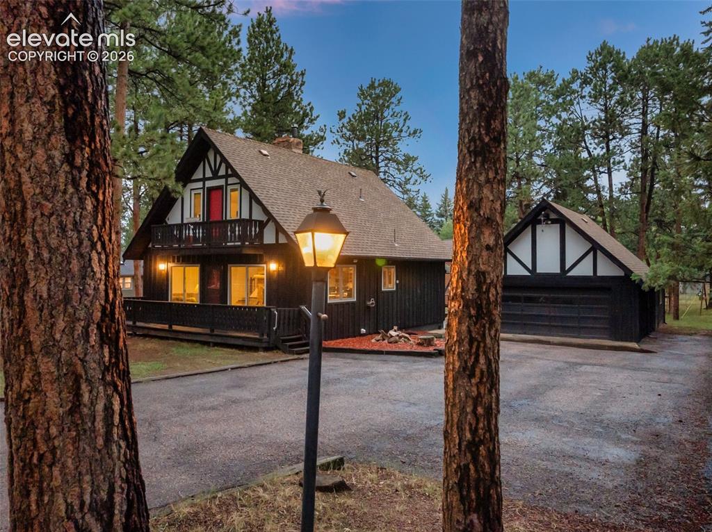 Image 3 of 40: Tudor-style exterior with dark vertical siding, white trim accents, and an