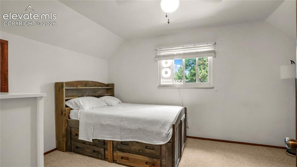 Image 32 of 40: 2nd upstairs bedroom, with white walls, sloped ceiling, and a window with b