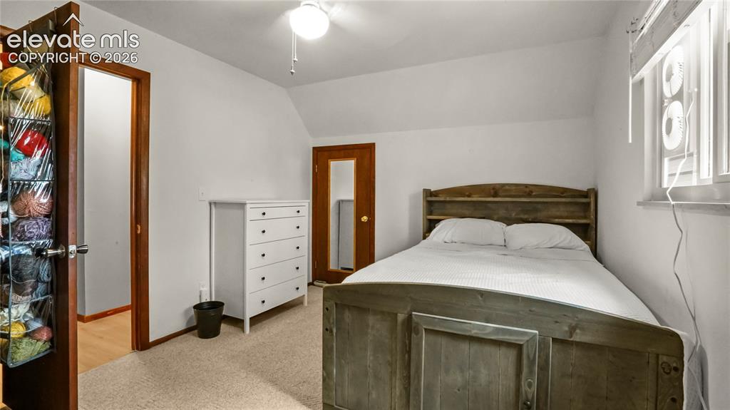 Image 33 of 40: 2nd upstairs bedroom, with white walls, sloped ceiling, and a window with b
