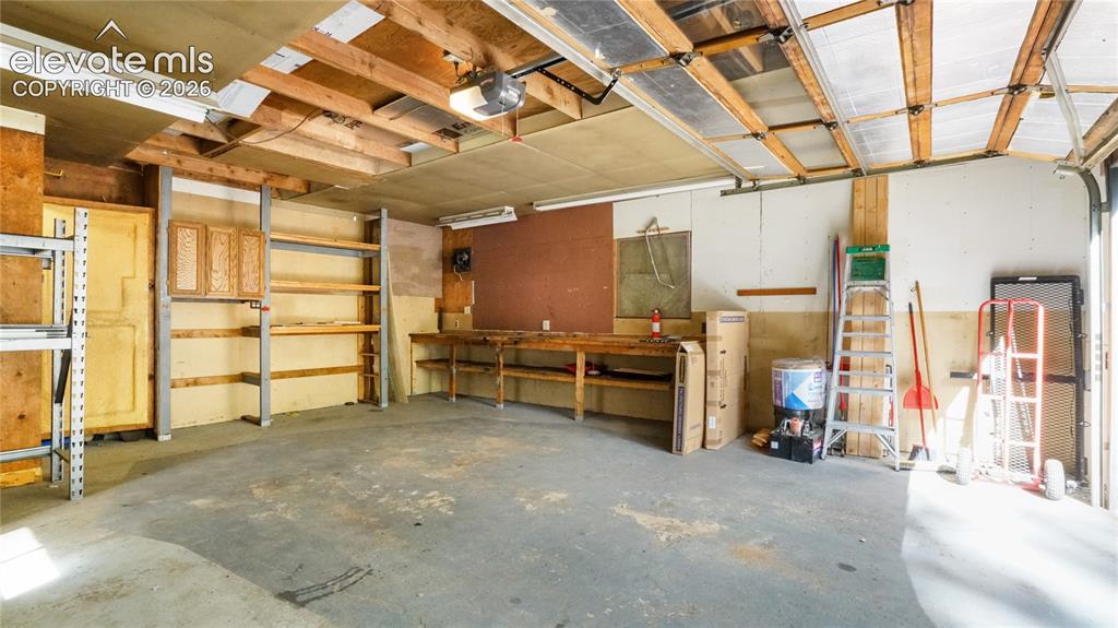 Image 35 of 43: Concrete flooring with exposed ceiling joists, built-in shelving, wood cabi