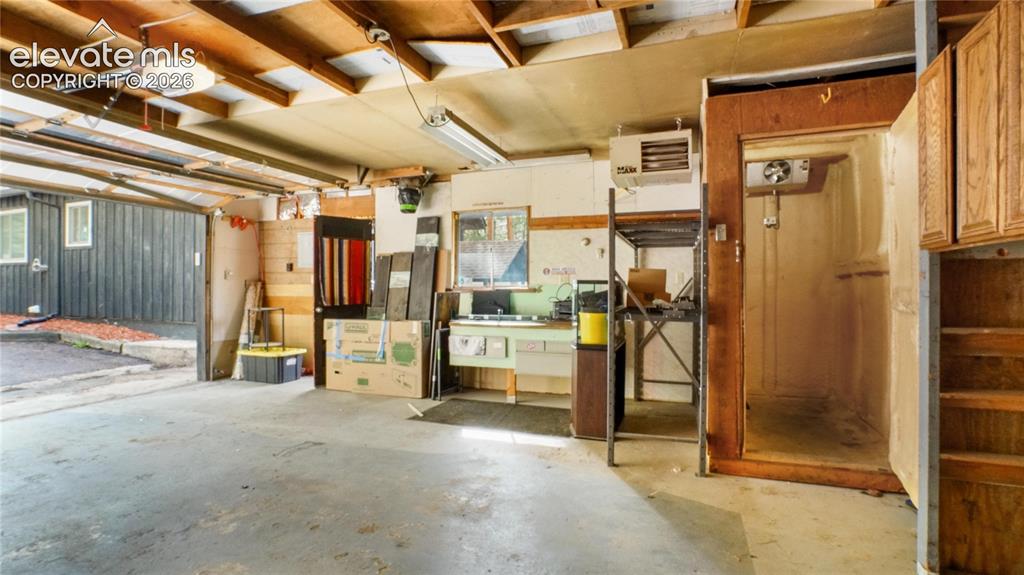 Image 36 of 43: Concrete floor, exposed wood beam ceiling, fluorescent lighting, attached c