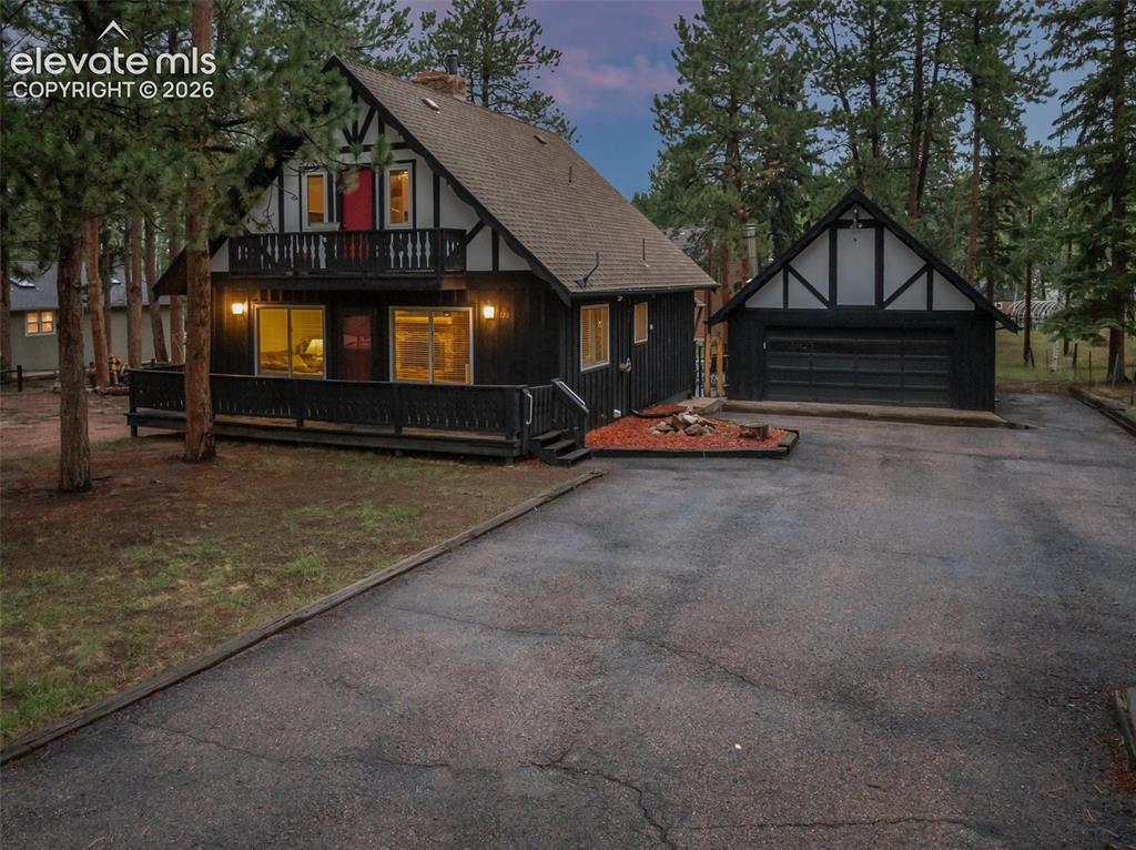 Image 8 of 40: Tudor-style exterior with dark siding and white trim accents, featuring a p