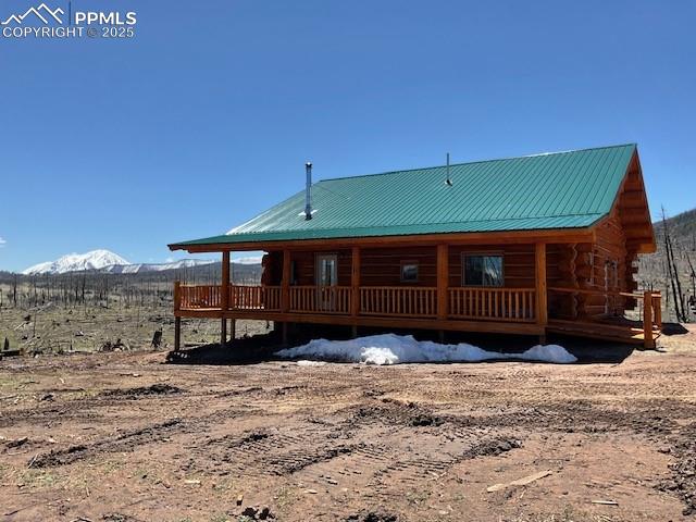 Image 5 of 45: side of house with a porch, a mountain view, log exterior, and metal roof