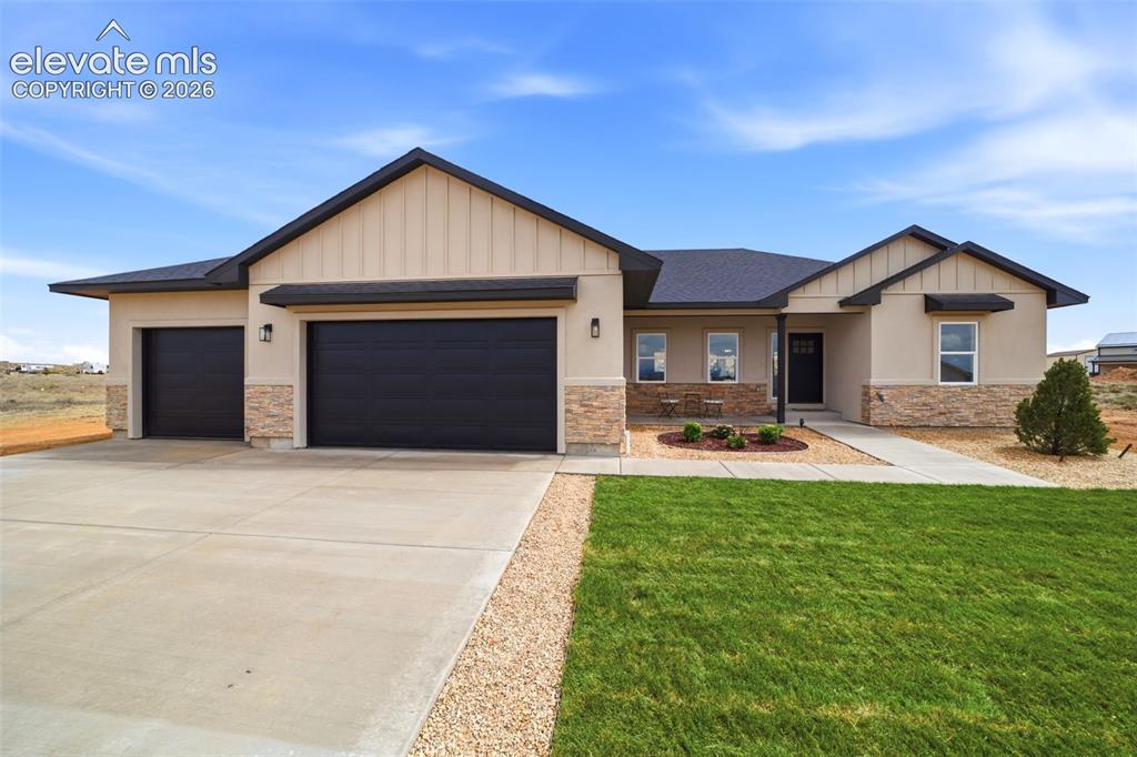 Image 1 of 26: Front of home with landscaped front yard, grass, rock, tree, and sprinkler 