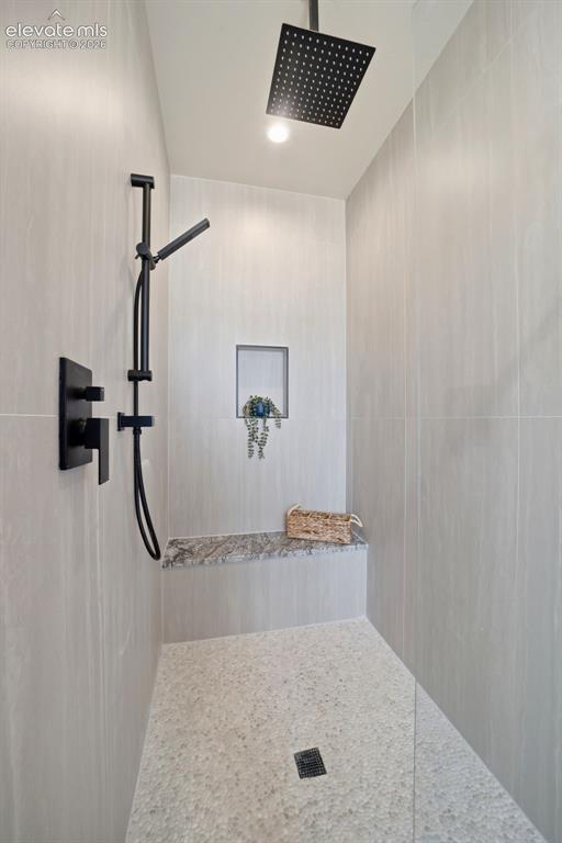 Image 15 of 26: Walk in shower with bench and glass door.