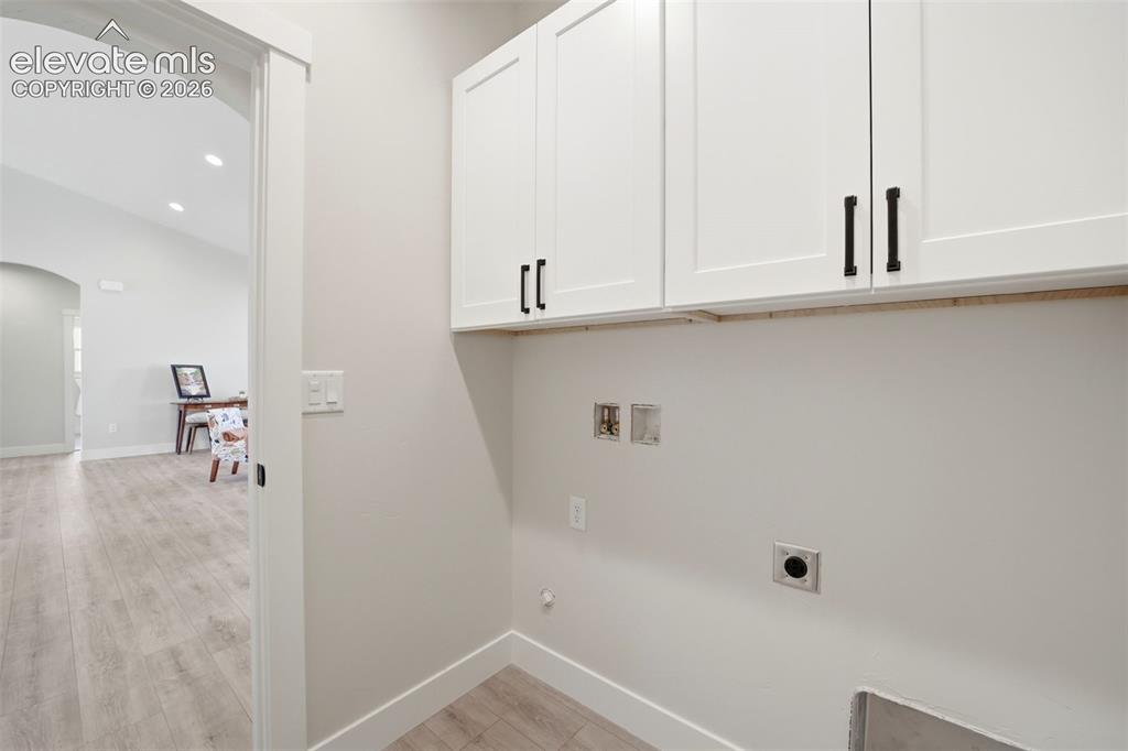 Image 23 of 26: Laundry room near garage enterance, with overhead cabinets.