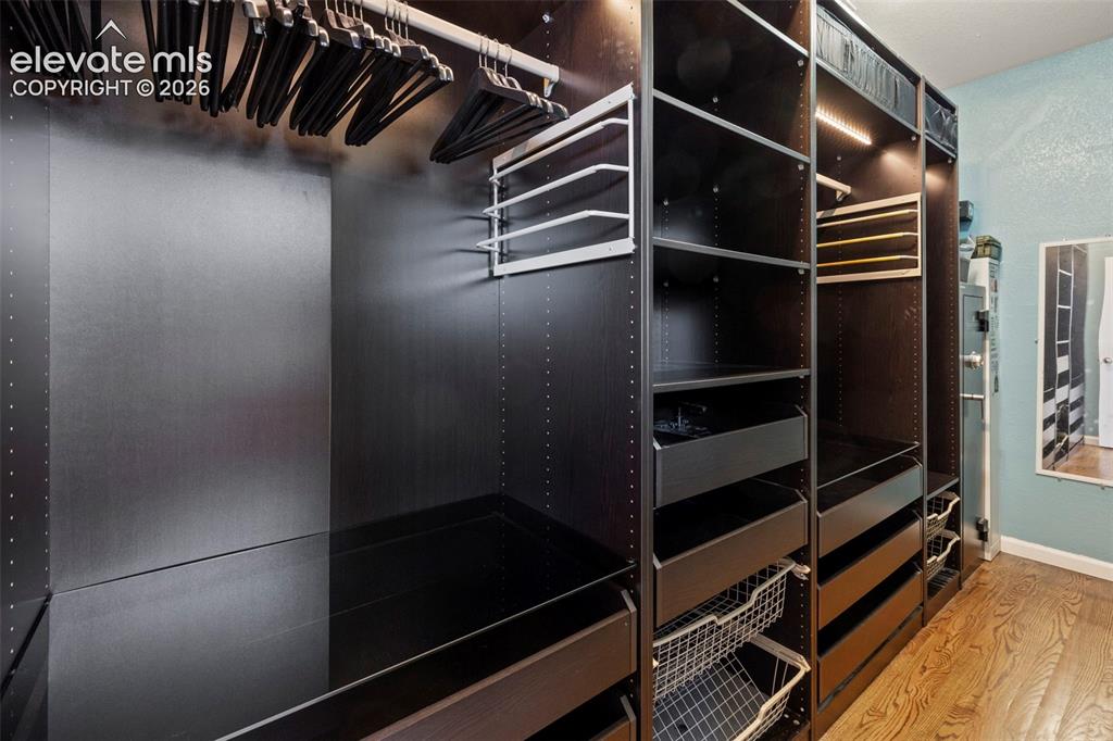 Image 15 of 50: Walk-in closet in the master suite with accent lighting and hardwood floors