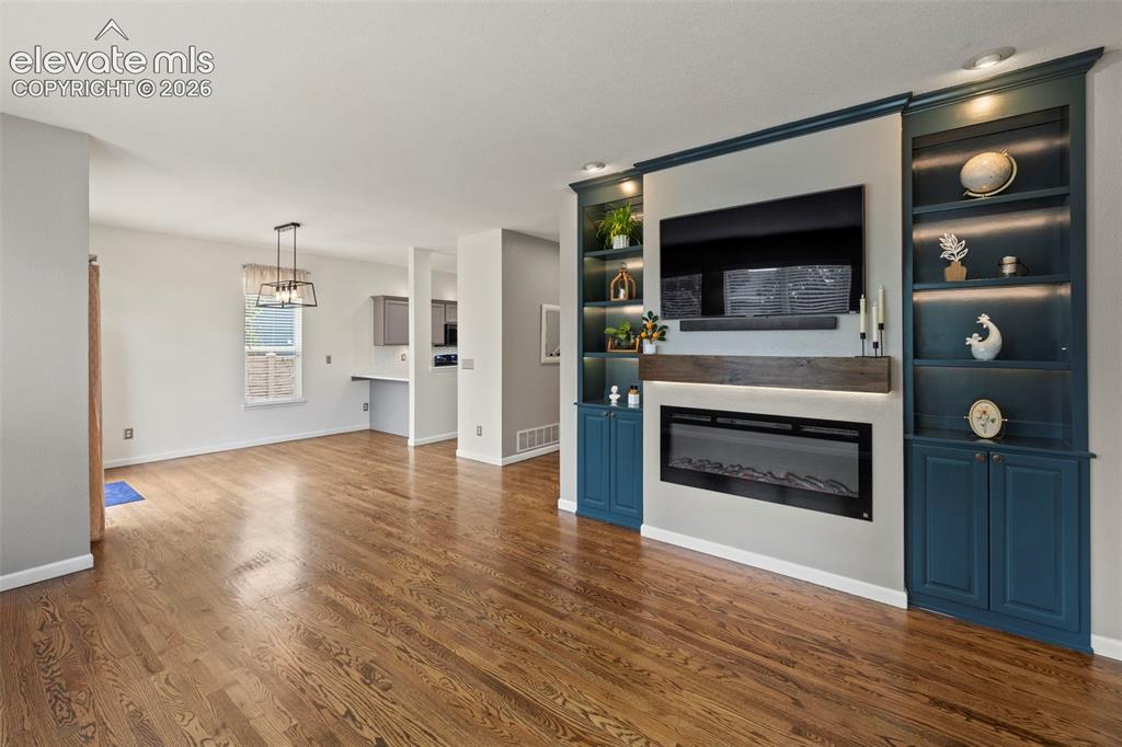 Image 2 of 50: Living room with custom built cabinets, electric fireplace, hardwood floors