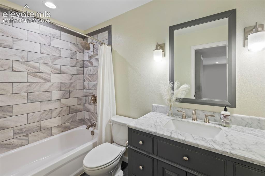 Image 25 of 50: Basement bathroom with tile floors, tile surround, granite counters and upd