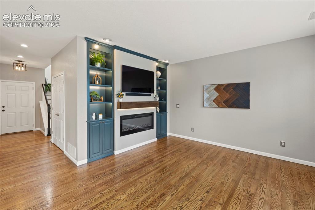 Image 3 of 50: Living room with custom built cabinets, electric fireplace, hardwood floors