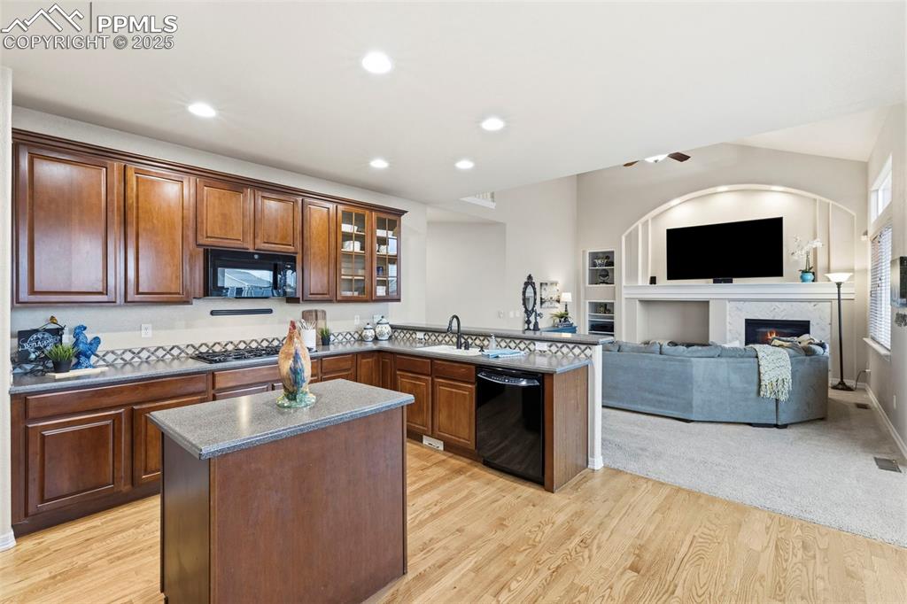 Image 10 of 46: Kitchen featuring a peninsula, black appliances, recessed lighting, a cente
