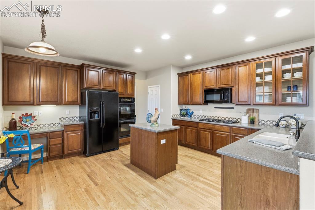 Image 11 of 46: Kitchen featuring brown cabinets, double ovens, a center island, recessed l