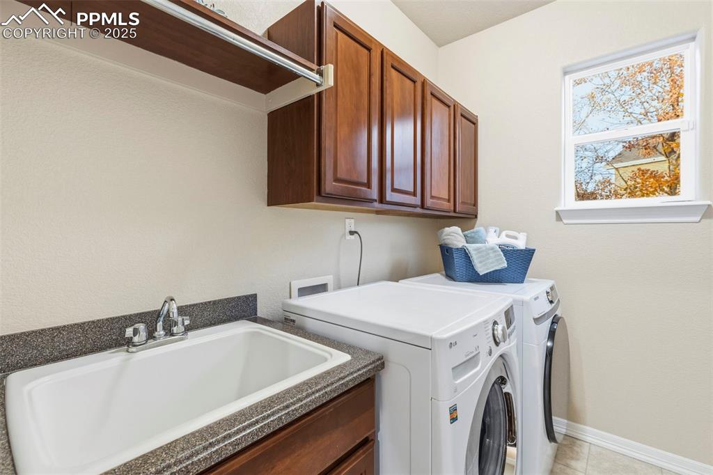 Image 15 of 46: Washroom with independent washer and dryer, cabinet space, and light tile p