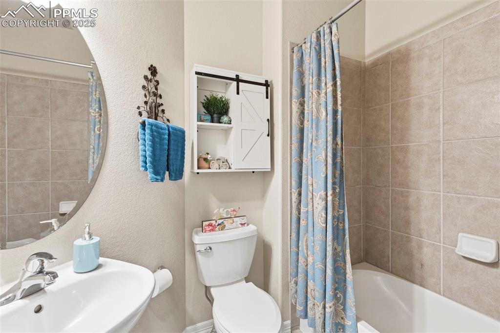 Image 16 of 46: Bathroom featuring a textured wall and shower / tub combo