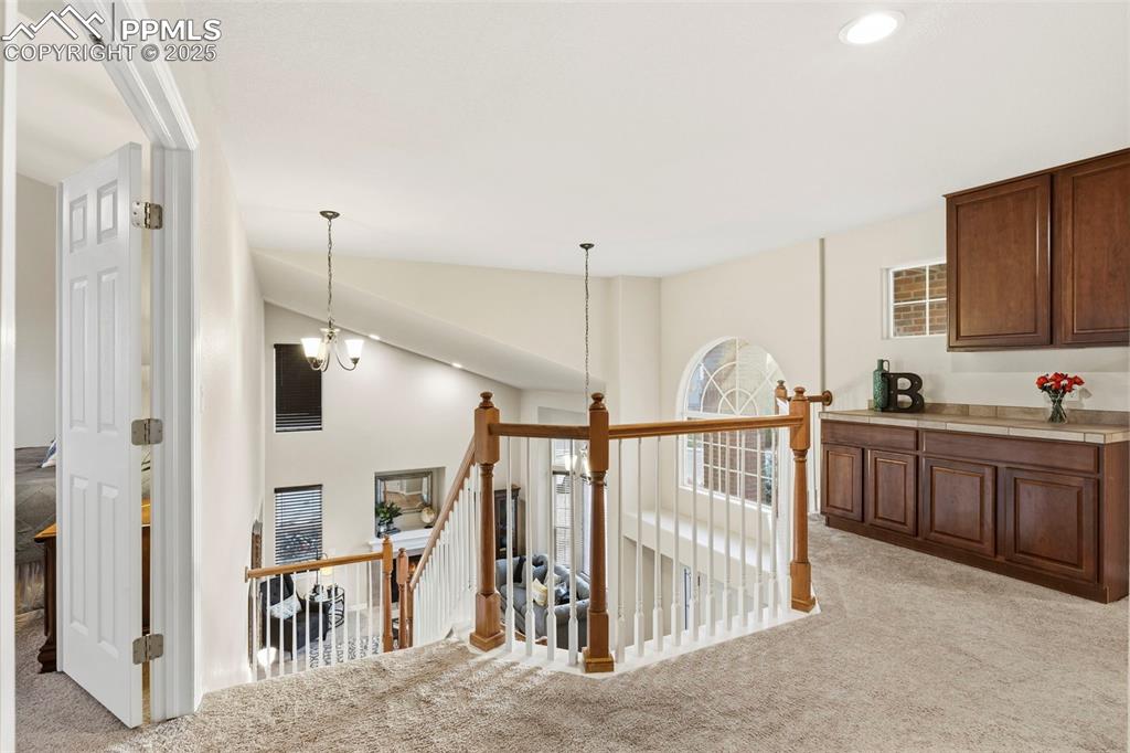 Image 19 of 46: Corridor featuring an upstairs landing, light colored carpet, high vaulted