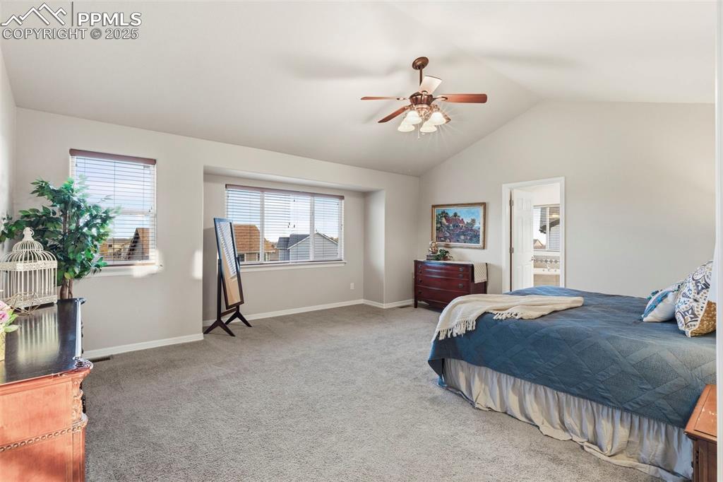 Image 21 of 46: Huge Primary Bedroom featuring carpet flooring, vaulted ceiling, ceiling fa
