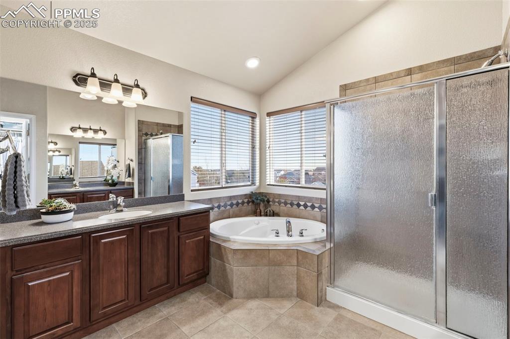 Image 23 of 46: Bathroom with a shower stall, a bath, vanity, light tile patterned flooring