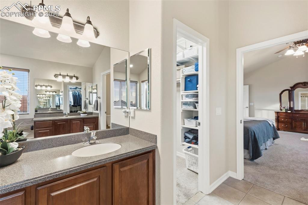Image 24 of 46: Full bath featuring a walk-in closet, vanity, light tile patterned floors,