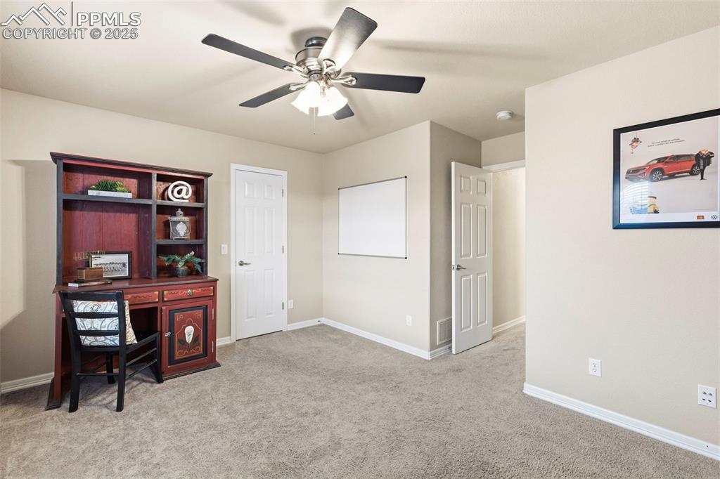 Image 31 of 46: Office space with light colored carpet and ceiling fan