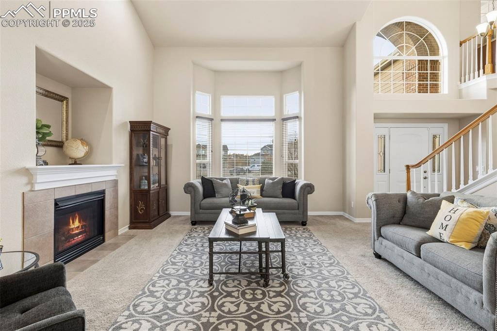 Image 4 of 46: Carpeted living area featuring a towering ceiling, stairway, and a tile fir