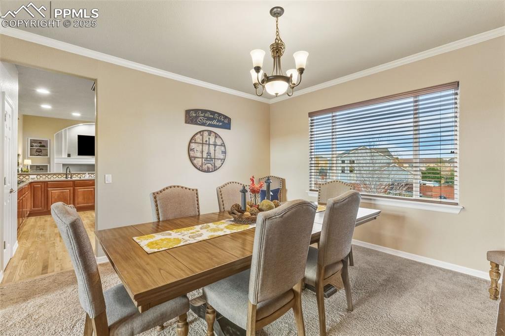 Image 6 of 46: Dining room with ornamental molding, light carpet, and a chandelier