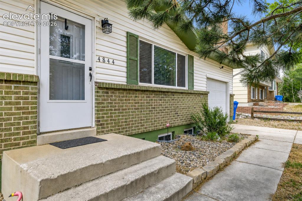 Image 1 of 26: Front entry featuring concrete steps, a white storm door, and contrasting g