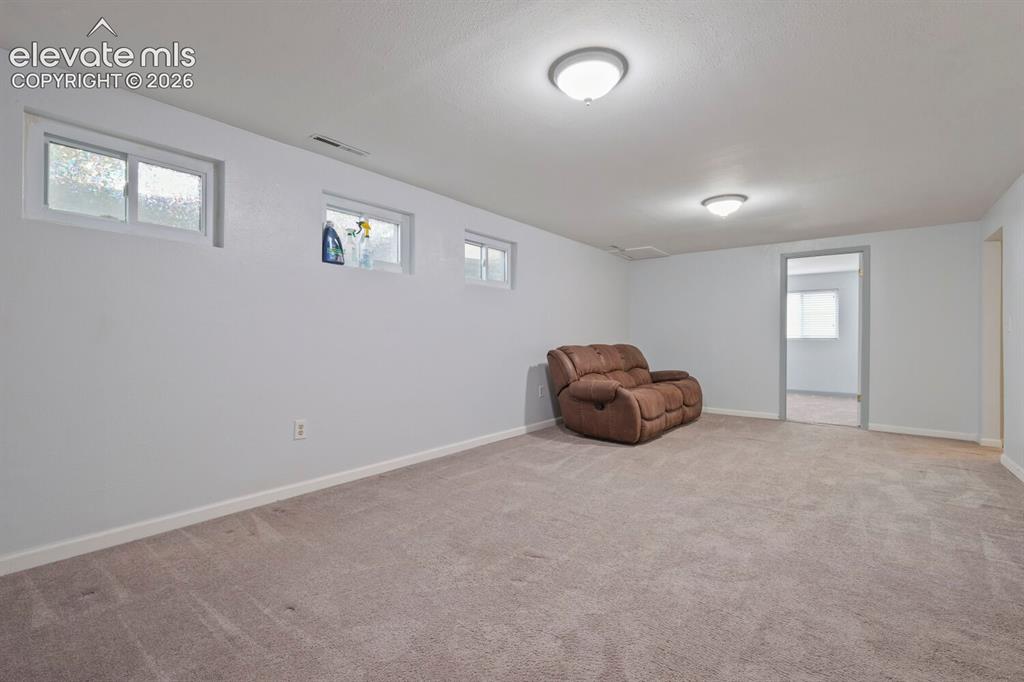 Image 10 of 26: Carpeted room with light gray walls, featuring three high-set windows, two