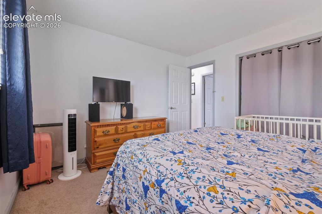 Image 14 of 26: Carpeted room with white walls, a white paneled door, and a window with dar