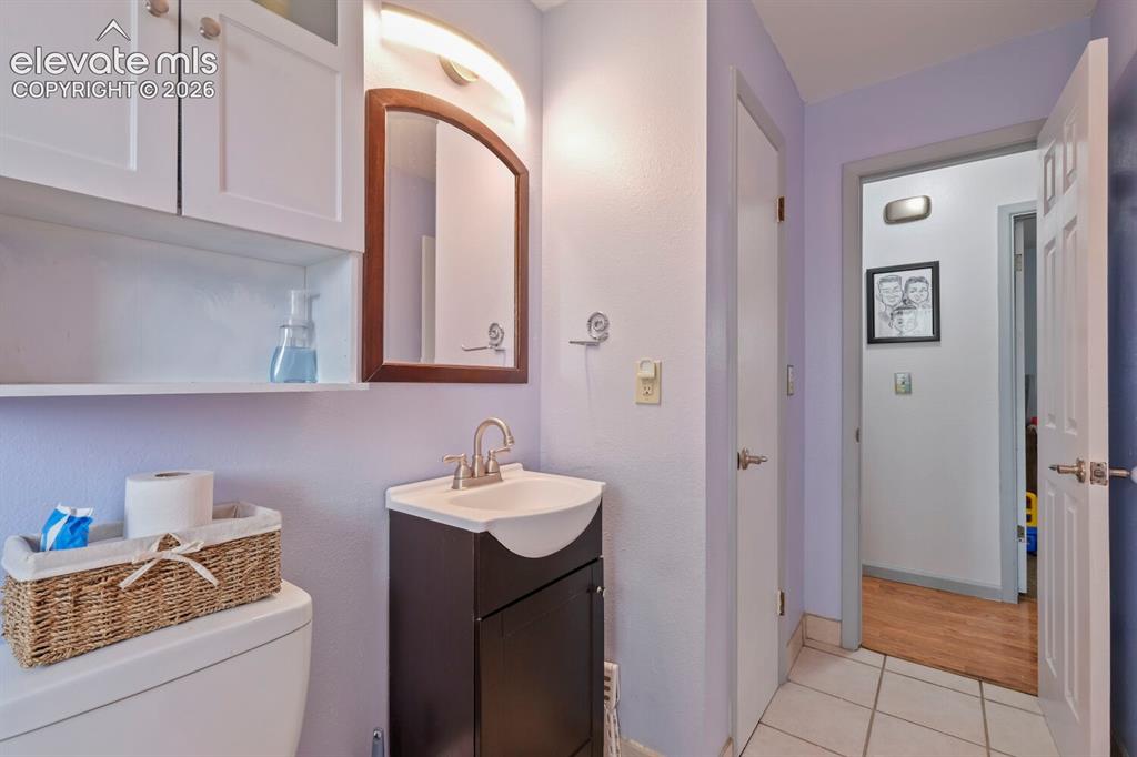 Image 16 of 26: Compact bathroom featuring a dark wood-finish vanity with an integrated sin