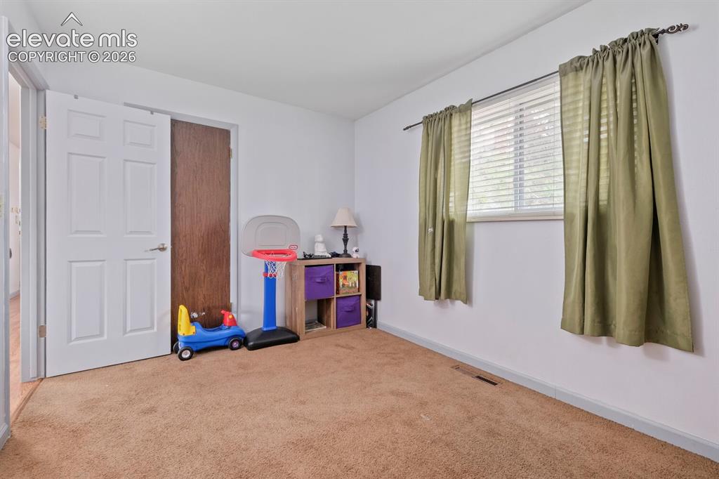 Image 17 of 26: Carpeted room featuring a white paneled door, a dark wood-finish door, and