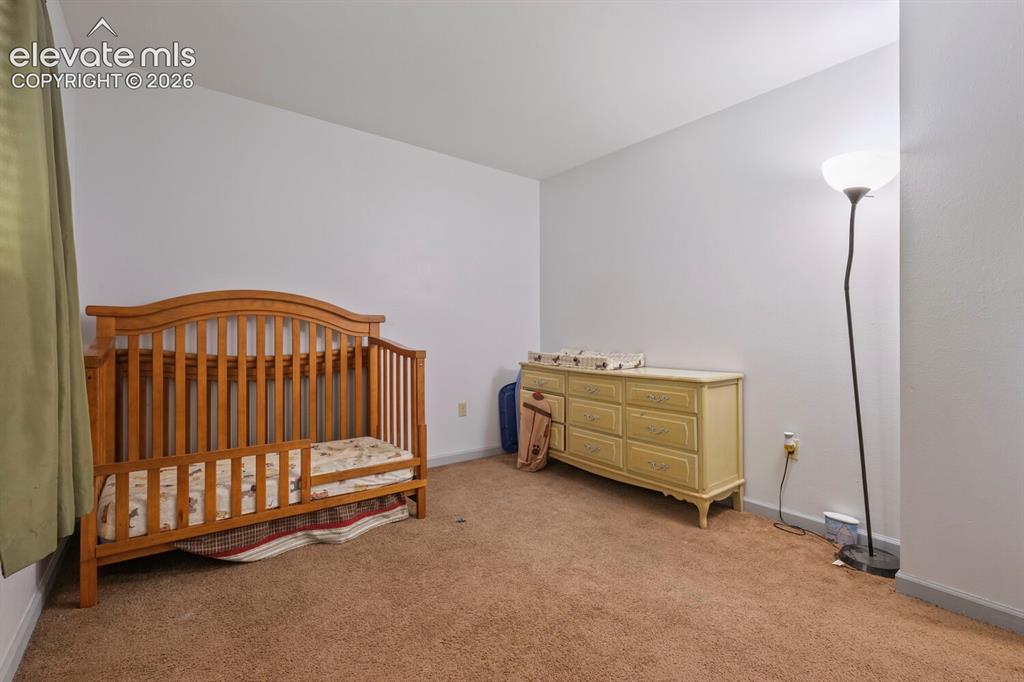 Image 18 of 26: Carpeted room featuring white walls and a window with light green curtains