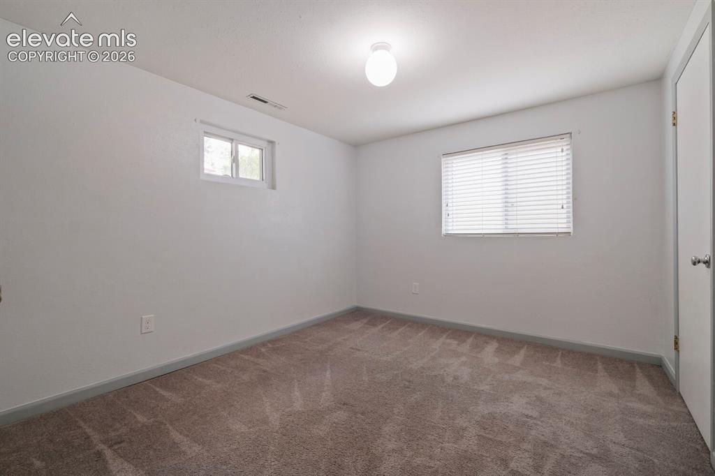 Image 19 of 26: Spacious interior room featuring white painted walls and neutral-toned patt
