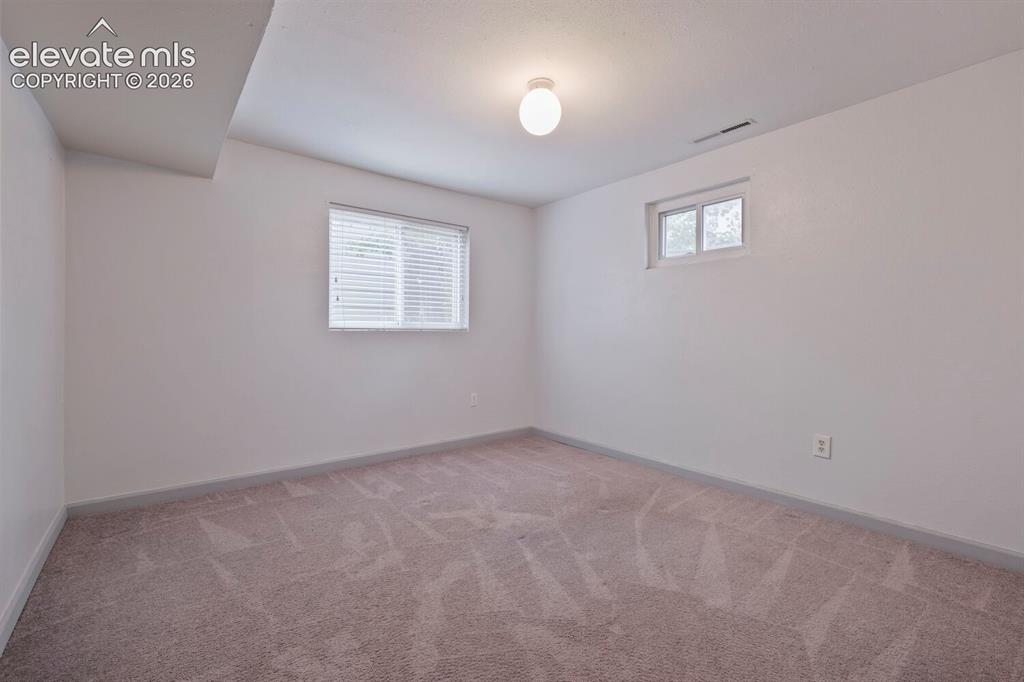 Image 21 of 26: Carpeted room featuring two windows with white trim, a flush-mount ceiling