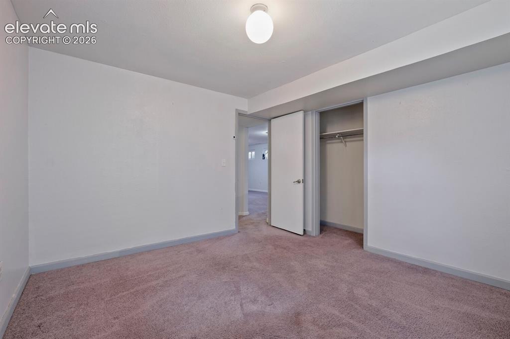 Image 22 of 26: Carpeted room featuring white walls, a built-in closet with hanging rod, an