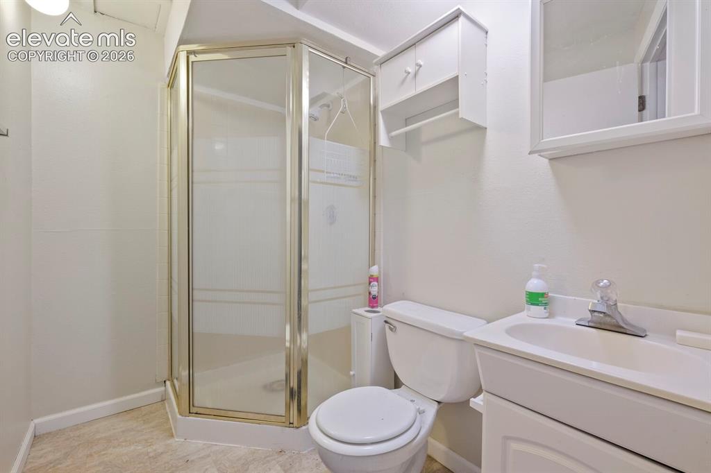 Image 23 of 26: Bathroom featuring a corner shower enclosure, white vanity with integrated