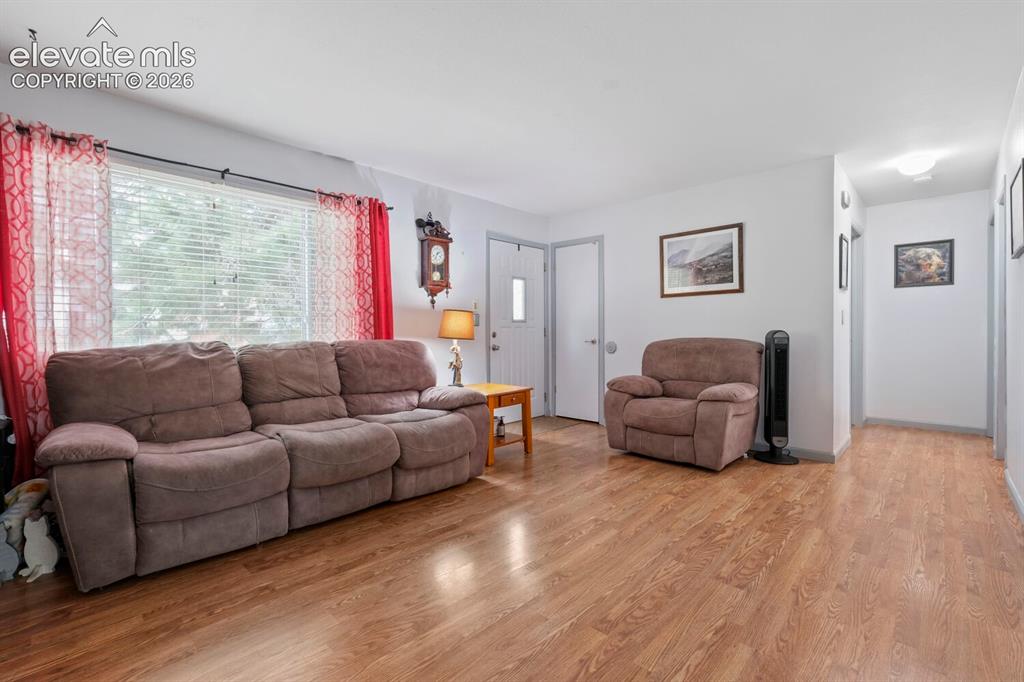 Image 3 of 26: Living area featuring wood-finish flooring, light-toned walls, and a large