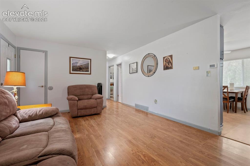 Image 6 of 26: Spacious living area featuring wood-finish flooring, light neutral wall pai