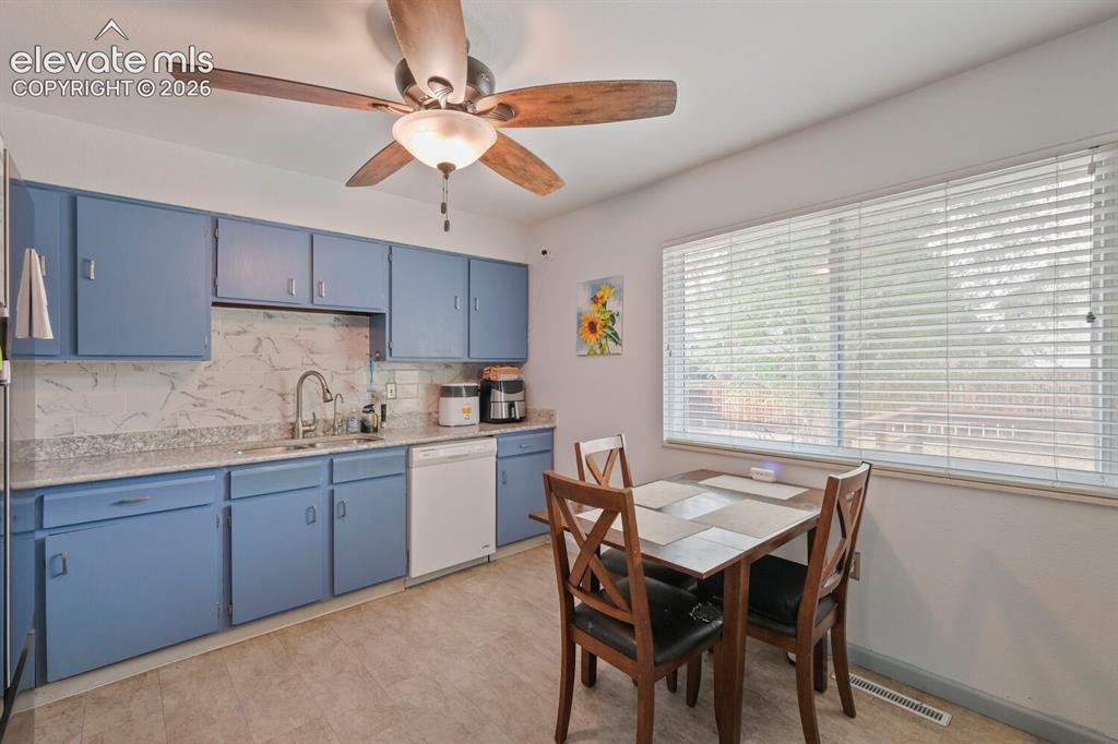 Image 8 of 26: Kitchen featuring blue cabinetry, light-toned countertops, tile backsplash,