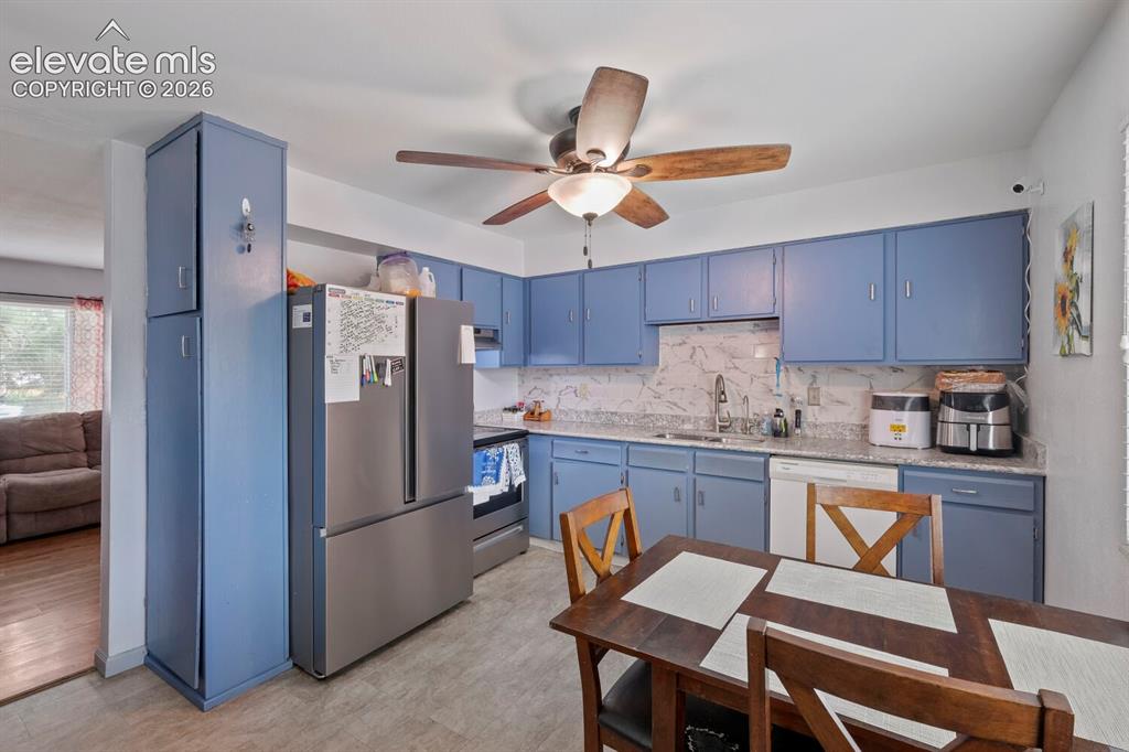 Image 9 of 26: Kitchen featuring blue cabinetry, granite-look countertops, and a full suit