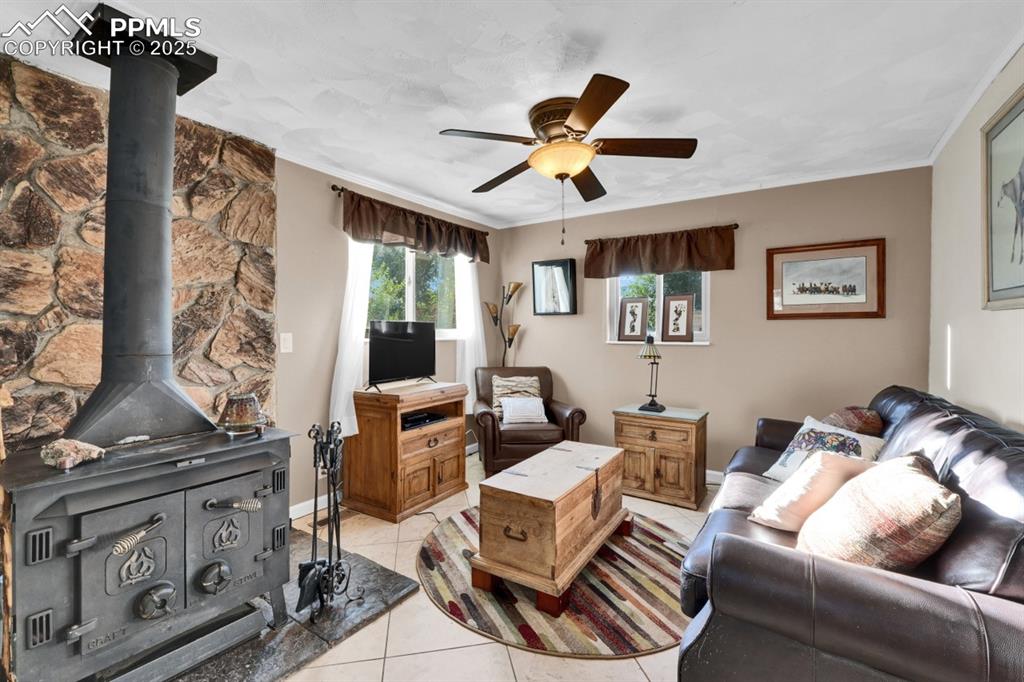 Image 9 of 24: Living area with a wood stove & ceiling fan