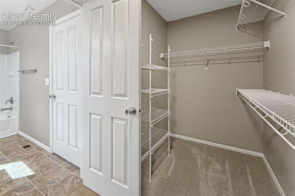 Image 24 of 41: Walk-in primary closet with built-in shelving and storage.
