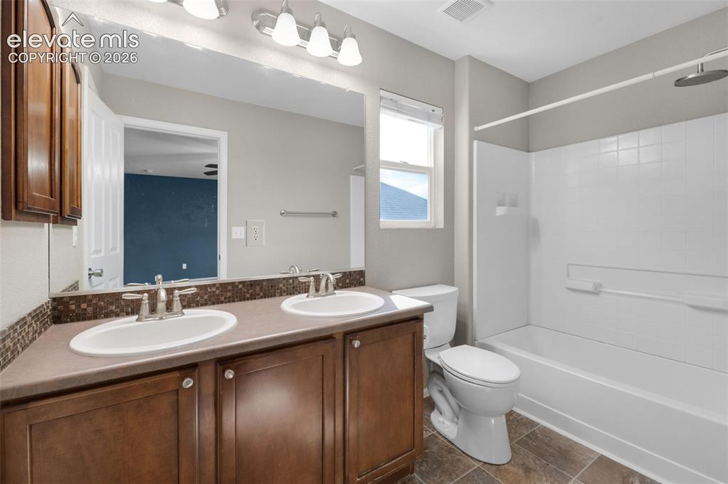 Image 25 of 41: En suite primary bathroom with double vanity and adjoining walk-in closet.